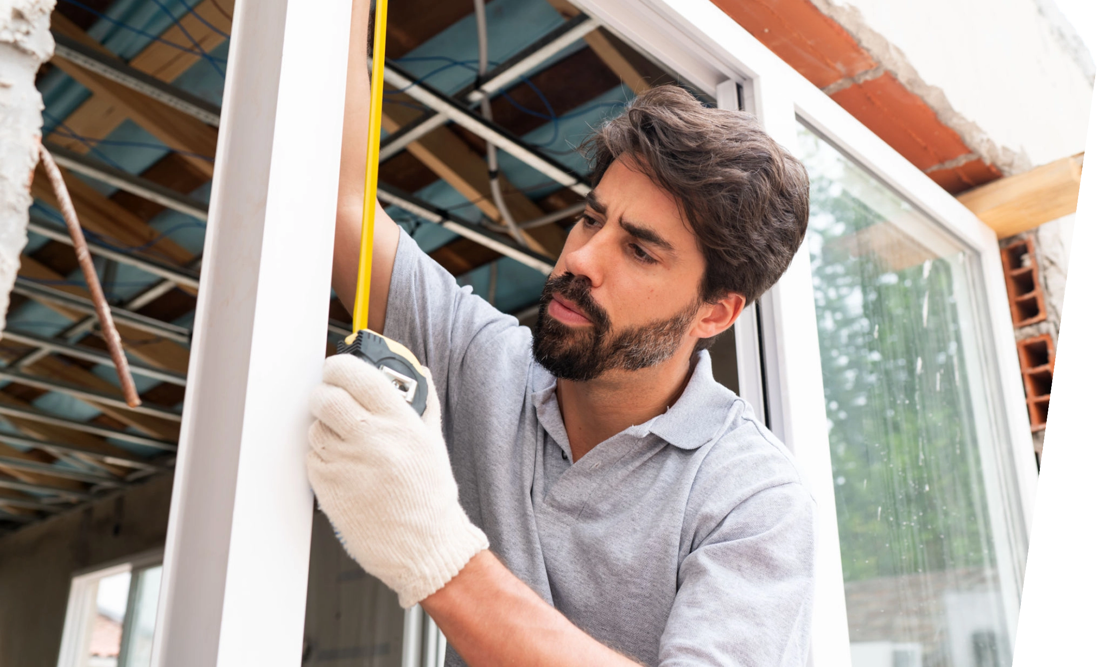 Man measuring window frame with tape measure.