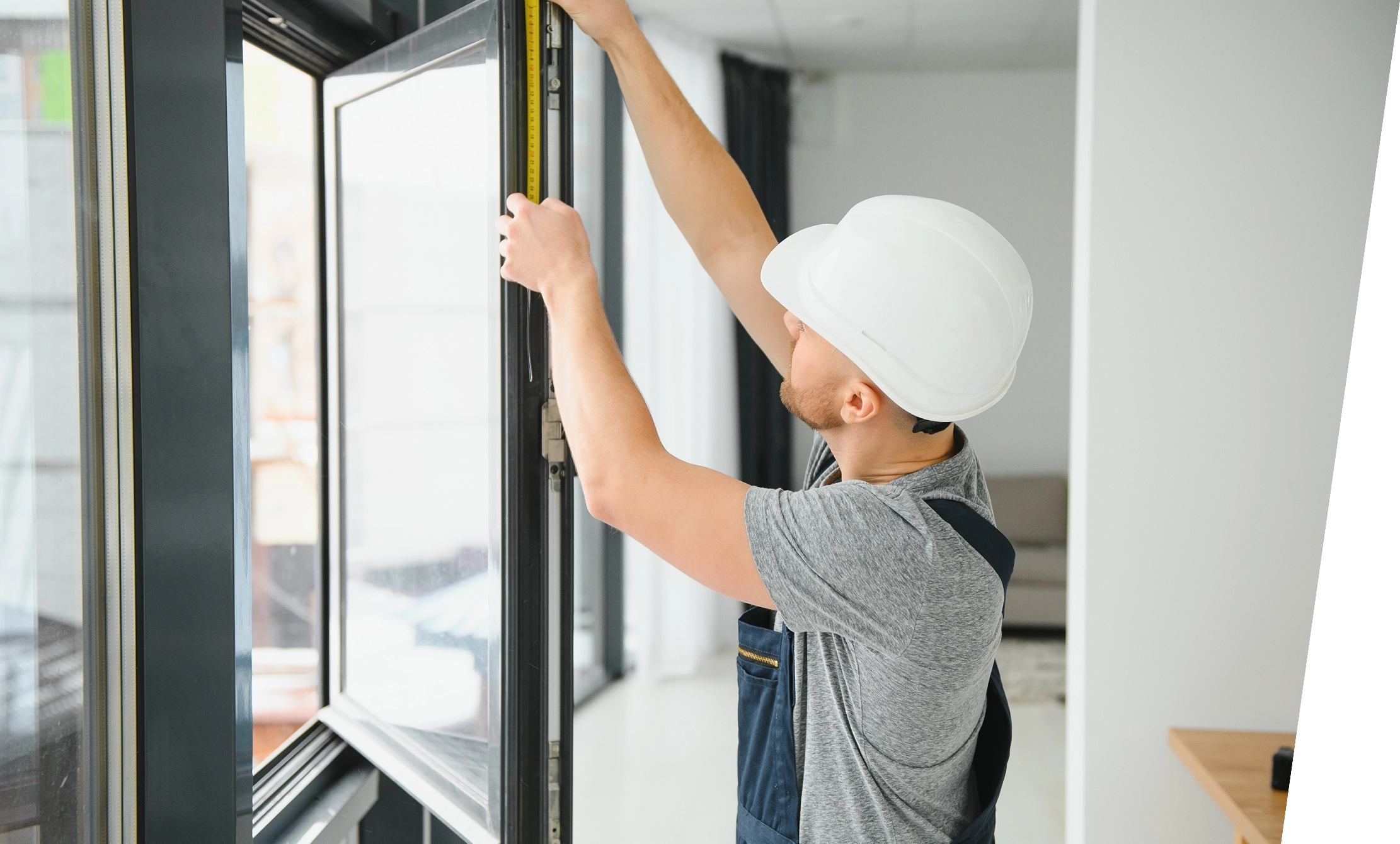 Worker measuring window with tape measure.