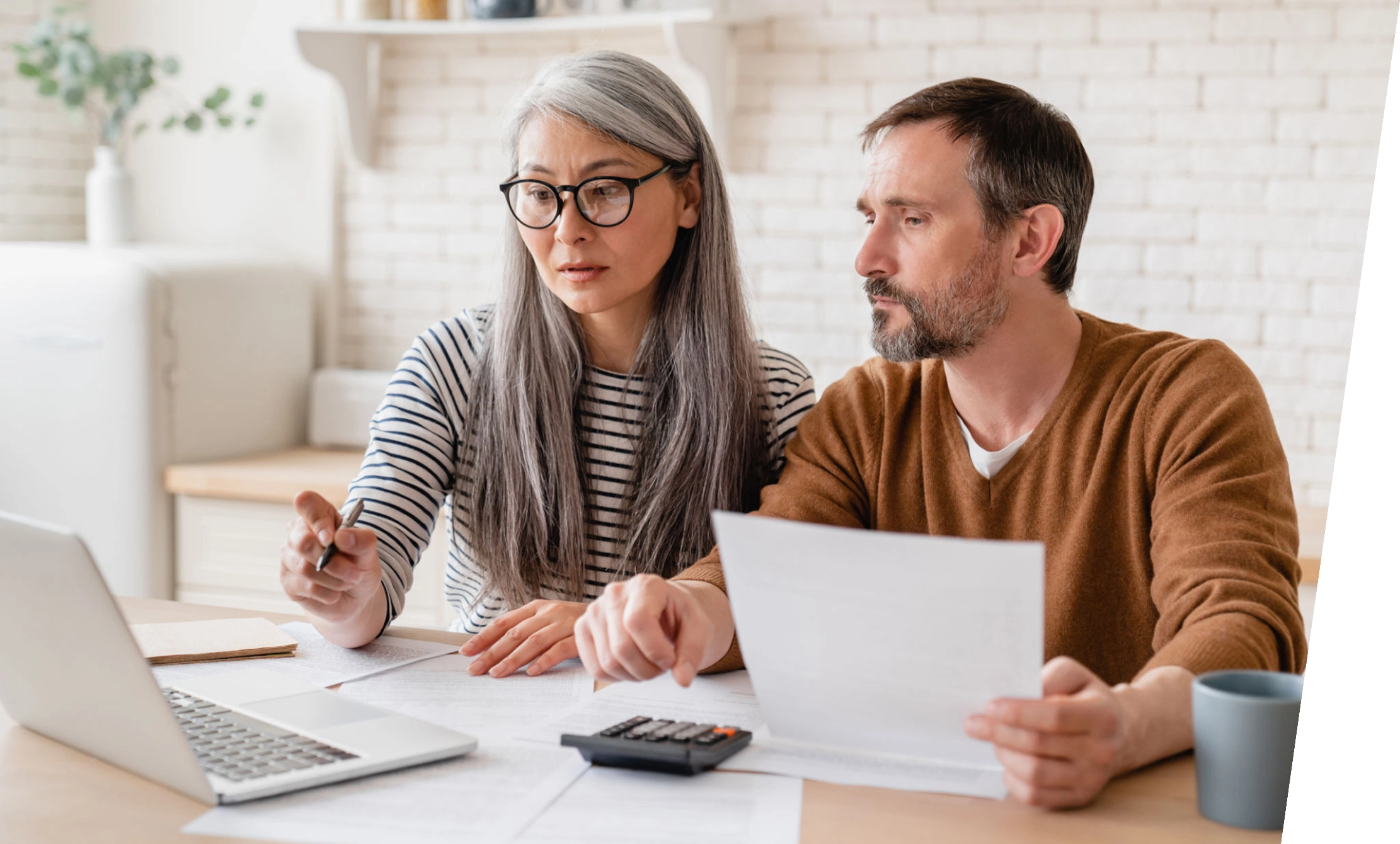 Couple reviewing documents at a laptop.