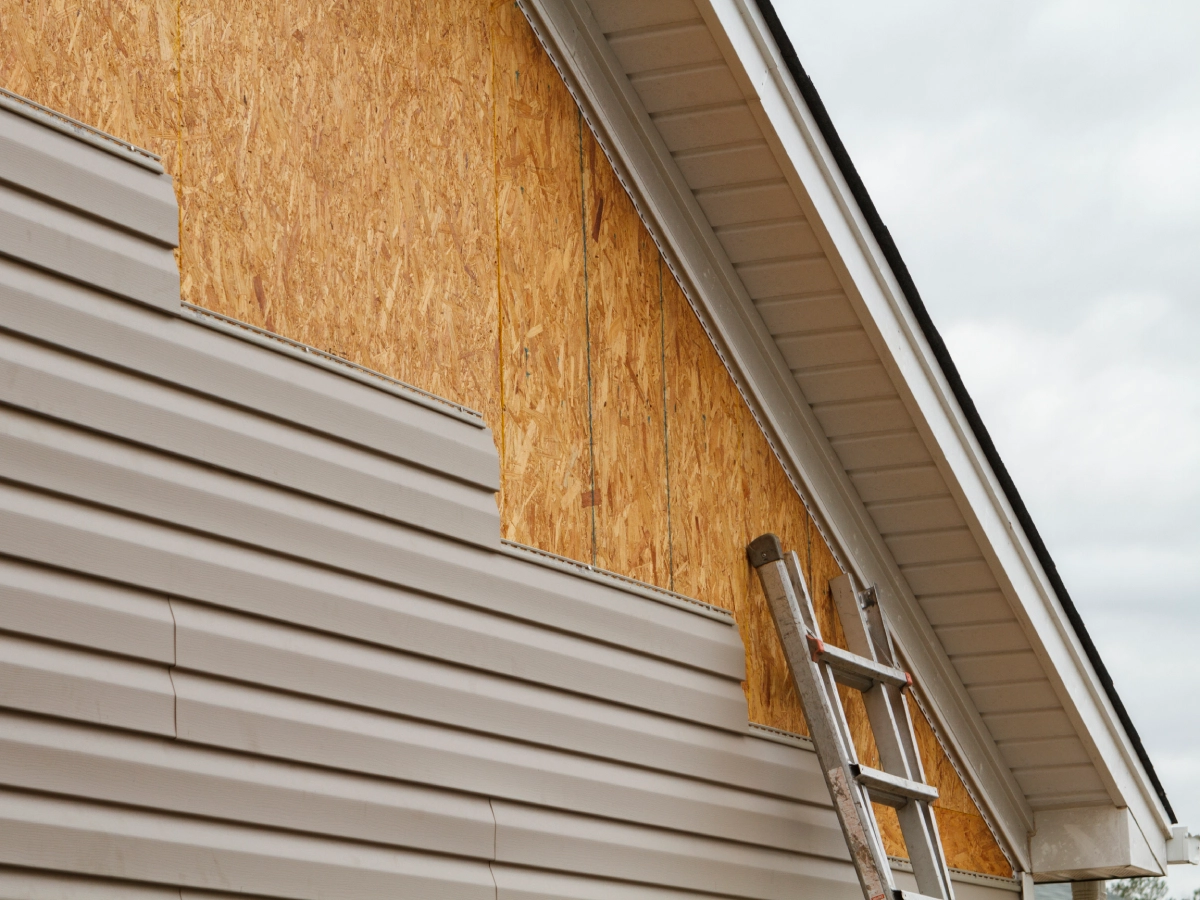 House siding installation with ladder on wall.